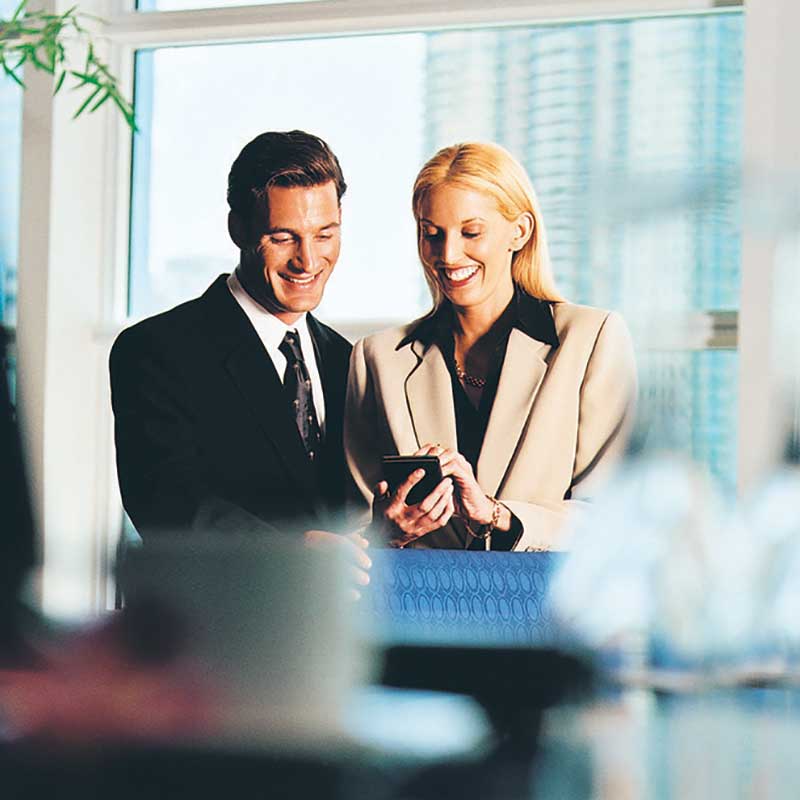 man and woman smiling as they view content on a mobile phone