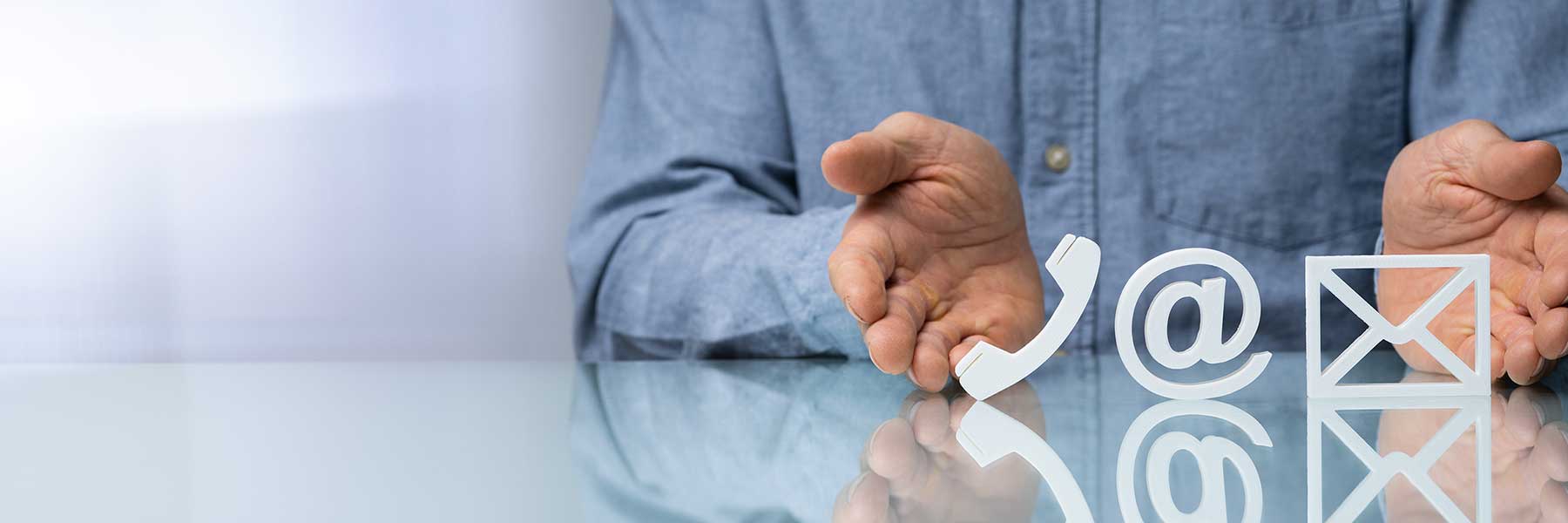 man's hands gesturing toward symbols for a phone, email and envelope